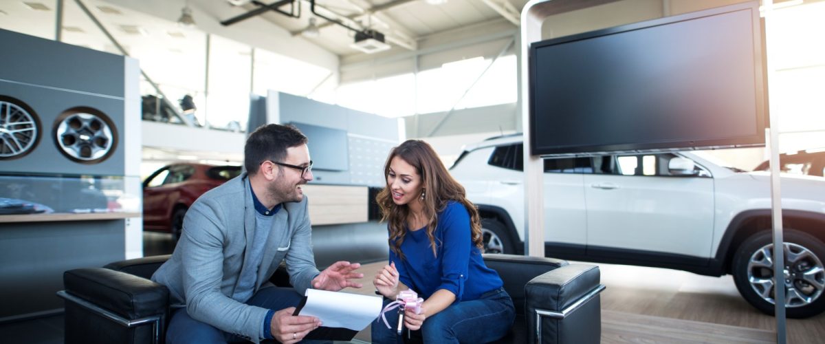 People at vehicle dealership buying new car.